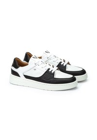 Zapatillas de cuero blancas y negras con detalles perforados, punta redonda, costuras en contraste y una suela de goma blanca. Cintas y logo en la lengüeta.