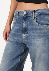 Ljusblå denimjeans med hög midja och vida ben, med fem fickor, kontrasterande sömmar och metallknäppning.