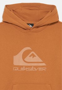 Sweatshirt castanho feito de um tecido suave, apresentando um grande logo branco da Quiksilver na frente, um capuz com cordão e um bolso canguru.