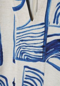 Katoenen stof met een witte basis, voorzien van blauwe abstracte patronen en lijnen, V-hals ontwerp en een ritsdetail. Getextureerd oppervlak.