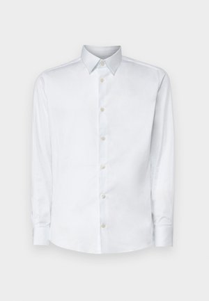 Chemise blanche à manches longues en tissu lisse, dotée d'un col classique, d'une patte de boutonnage et de poignets avec boutons, présentée sur un fond uni.