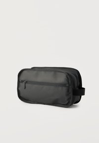 Συμπαγής μαύρο τσαντάκι καλλυντικών με μπροστινή τσέπη με φερμουάρ και πλευρική λαβή, κατασκευασμένο από ανθεκτικό ύφασμα, παρουσιάζεται σε απλό ανοιχτό φόντο.