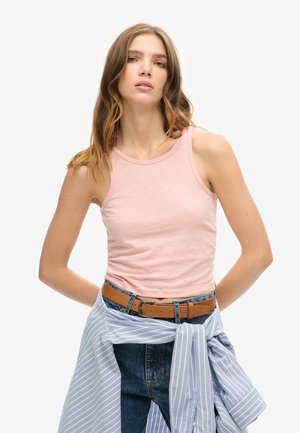 Lichtroze tanktop van zacht materiaal, gecombineerd met hoge spijkerbroek en een blauw-wit gestreepte blouse om de taille geknoopt.