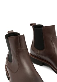 Brązowe skórzane botki Chelsea z elastycznymi bocznymi panelami, okrągłym noskiem i niskim, złożonym obcasem z kontrastowym przeszyciem.