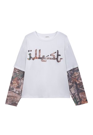 Chemise blanche à manches longues avec des manches superposées à imprimé camouflage et un texte avec motif camouflage sur la poitrine.