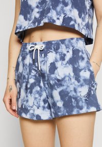 Tmavě modré a světle modré tie-dye šortky vyrobené z měkké bavlny, s elastickým pasem a šňůrkou a bočními kapsami. Akcent s logem Nike.