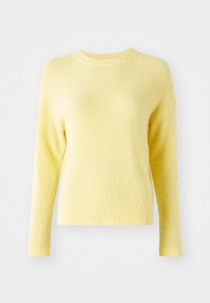 Pull jaune avec une texture douce et duveteuse, col rond et manches longues. Ourlets et poignets côtelés. Design simple sans motifs visibles.