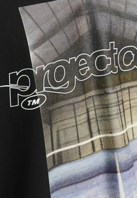Černé tričko s grafickým potiskem a textem "projekt". Pozadí ukazuje geometrický vzor v tlumených barvách s mírně texturovaným povrchem.