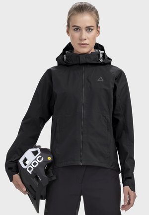 Schwarze wasserdichte Jacke mit Kapuze, vorne mit Reißverschluss und seitlichen Taschen. Die tragende Person hält einen schwarzen Fahrradhelm mit weißen Akzenten.