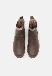 Hnědé kožené zimní boty po kotníky s chlupatým hnědým podšívkou, elastickými bočními panely a šitým lemováním, s hladkým povrchem a zaoblenou špičkou.