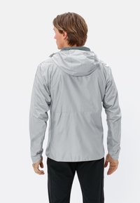 Veste de pluie légère, argentée, avec capuche, manches longues et texture lisse. Présente un dos uni avec une coupe mi-longue.