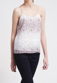 Biały top na cienkich ramiączkach z kwiatowym wzorem w odcieniach różu i niebieskiego, o luźnym kroju i zwiewnym designie, zestawiony z ciemnymi dżinsami.