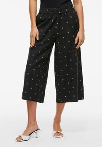 Melnie īsie bikses ar elastīgu jostu, ar ģeometrisku rakstu un smalkiem akcentiem. Audums izskatās viegls un mīksts.