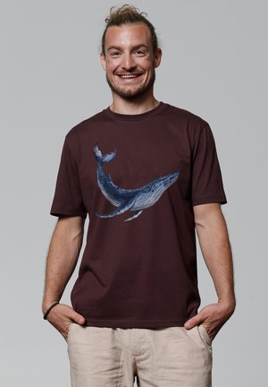Donkerburgundy t-shirt met een gedetailleerd ontwerp van een blauwe walvis op de voorkant. Korte mouwen, ronde hals, gemaakt van zachte katoen.