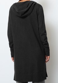 Lång, mörkgrå hoodie gjord av mjukt material. Har en rymlig huva, långa ärmar och sidospår för lätt rörelse.