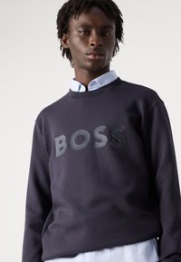 Ναυτικό φούτερ με στρογγυλή λαιμόκοψη, που διαθέτει γυαλιστερό λογότυπο "BOSS" στο κέντρο. Μίγμα βαμβακιού, με μαλακή υφή και άνετη εφαρμογή.