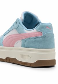 Zapatillas de ante azul claro con detalles en rosa y paneles blancos. Presentan punta redondeada, cuello acolchado y suela de goma texturizada. Se observa la marca Puma.