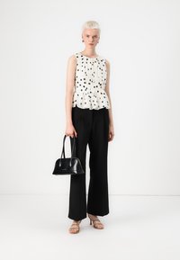Valge peplum-särg mustade täppidega, mustad laiad püksid, must käekott ja sukad nude tooni. Sile kangas, struktureeritud disain, minimalistlikud aktsendid.