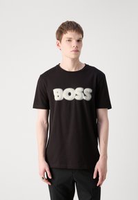 Svart bomull T-shirt med en djärv, vit "BOSS"-logotyp i en mjuk, puffig textur, rund halsringning och korta ärmar.