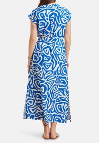 Maxikleid aus leichtem Stoff mit blau-weißer, abstrakter Musterung, kurzen Ärmeln und tailliertem Bund. Knielang mit seitlichen Schlitzen.