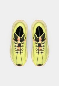 Αθλητικά παπούτσια σε λάιμ πράσινο με ελαφρύ πλέγμα πάνω μέρος, μαύρα κορδόνια και μαξιλαρωμένη σόλα με πορτοκαλί λεπτομέρεια στη φτέρνα.