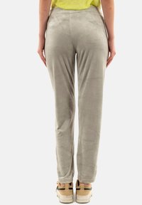 Pantalones de terciopelo gris con una textura suave, de corte ajustado y cinturilla elástica, combinados con zapatillas beige con una franja negra de acento.