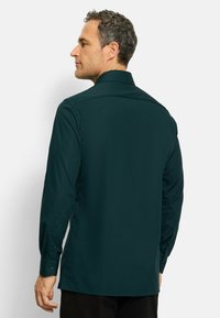 Donkerblauwe langesleeve shirt met knoopmanchetten en een spitse kraag. Glad stof met een eenvoudig ontwerp en een getailleerde pasvorm.