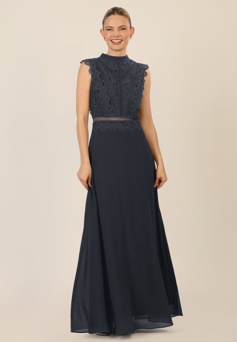 Abito blu navy con corpino in pizzo, bordi ondulati, scollatura alta e gonna fluida. Presenta maniche a cappuccio e dettagli in pizzo intricati.