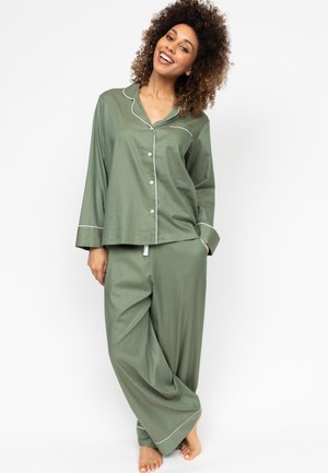 Olijfgroen pyjamastel van zacht materiaal. Met een knoopshirt met een zak en broek met wijde pijpen en witte piping accenten.