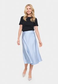 Črn kratkosrajčni top v kombinaciji z svetlo modro satenasto midi krilo. Model nosi svetleče petke z usnjatim vrhom. Gladek material in tekoč dizajn.