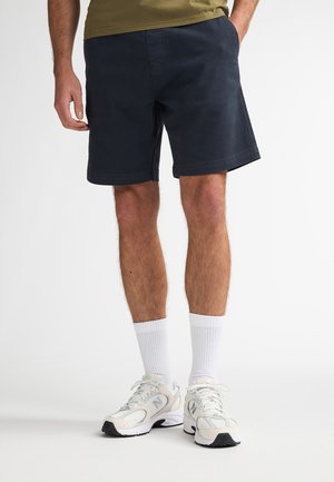 Donkerblauwe korte broek van katoen, met een rechte snit, zijzakken en een nette zoom. Gecombineerd met witte sportsokken en sneakers.