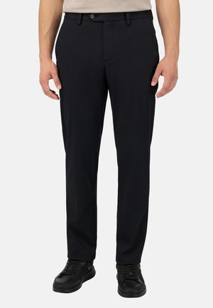 Pantalones negros hechos de un tejido de mezcla de algodón, con un diseño de frente plano, bolsillos estándar y un ajuste clásico, combinados con zapatillas negras.