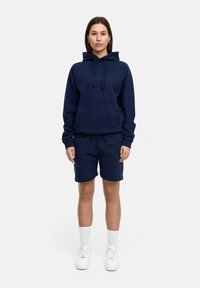 Navy blue cotton hoodie with a front pocket, drawstrings, and matching cotton shorts. Paired with white sneakers and crew-length socks.
