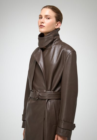 Bruine leren trenchcoat met een hoge kraag, ceintuur in de taille en grote revers. Heeft een gladde textuur en zijzakken.