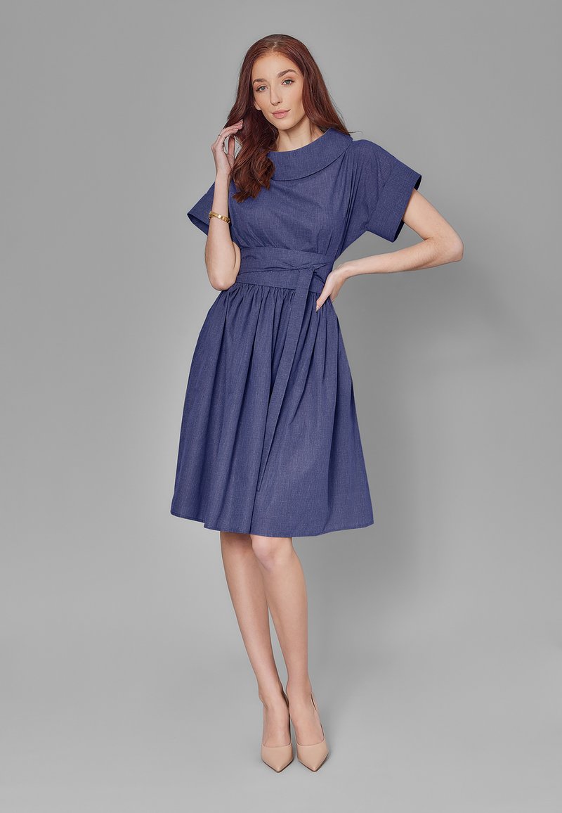 Jeansowa sukienka w głębokim granacie z plisowaną spódnicą, krótkimi rękawami, szerokim kołnierzem i związanym paskiem w talii; gładka tekstura, do kolan.