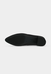Semelle d'une chaussure noire à bout pointu avec une semelle texturée et un petit talon bloc, présentée sur un fond blanc uni.