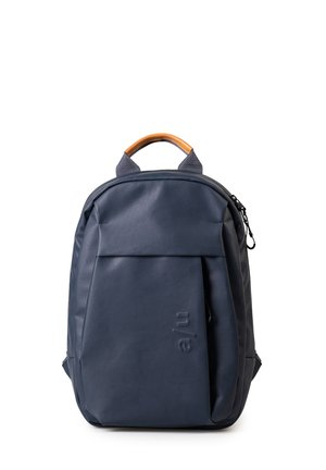 Zaino blu navy con una texture liscia, un manico superiore in pelle marrone, tasca frontale e un logo inciso in modo sottile sul lato.