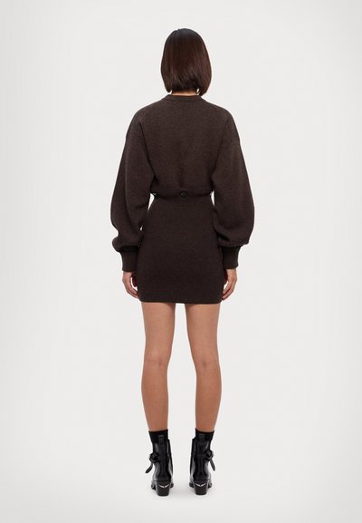 Brun strikket kjole med lange, puffede ærmer, en tæt talje og mini-længde, med en knapdetalje bagpå. Sorte ankelstøvler.