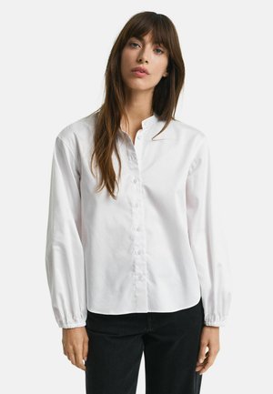 White button-up shirt with a mandarin collar, long puffed sleeves, and a slightly curved hem. Made of smooth, lightweight fabric.