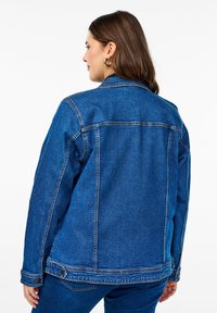 Jeans jakna u srednje plavoj boji s klasičnim krojem, s oštrim kragnom, kontrastnim šavovima i dugmadi na rukavima.