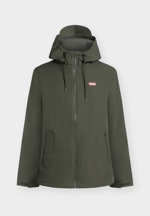 Veste imperméable à capuche de couleur vert foncé avec fermeture éclair frontale, cordons ajustables, deux poches latérales et petit logo rectangulaire Hunter sur la poitrine.