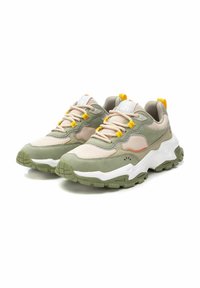 Zapatillas con una parte superior de malla beige, detalles de ante verde, suela gruesa blanca y verde, cordones amarillos y un pequeño logo en la lengüeta.