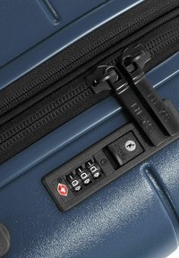 Navy hard-shell suitcase featuring dual black zippers, a combination lock with a red logo, and textured surface details for grip.