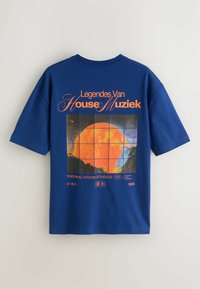 Blå t-shirt med orange tekst "Legendes Van House Muziek" og en grafik af en orange sol over et landskab opdelt af gitterlinjer på bagsiden.
