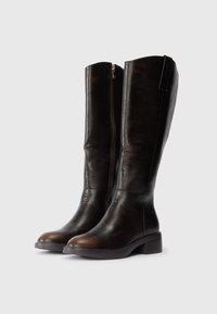 Bottes en cuir marron foncé montantes avec une fermeture éclair sur le côté et un talon carré. Texture lisse, coutures minimales et design à bout rond.
