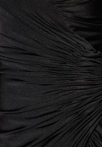 Černá tkanina s nabíranou strukturou, která obsahuje jemné záhyby a decentní lesk, vytvářející hloubku a pohyb v materiálu.