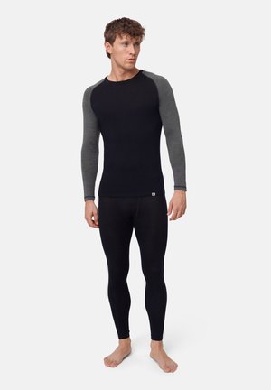 Svart långärmad topp med grå raglanärmar, kombinerad med svarta leggings. Tyget verkar slätt och elastiskt, lämpligt för träningskläder.