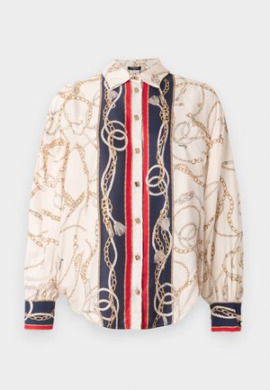 Silkebluse med en cremefarvet base, der har mønstre af guld kæder og reb. Marineblå og røde accenter langs knapstolpen og manchetterne.