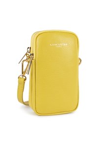 Borsa per telefono in pelle gialla con chiusura a zip, accessori in oro e tracolla regolabile. Presenta una superficie testurizzata e un logo impresso.