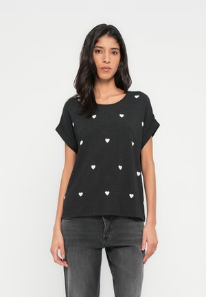 Schwarzes T-Shirt mit kurzen Ärmeln, das über den Körper verteilte, weiße Herzmuster aufweist, mit lockerem Schnitt und rundem Ausschnitt. Passt gut zu grauen Jeans.